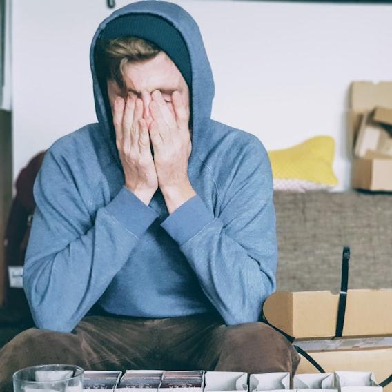 Emprendedor frustrado cubriéndose la cara entre cajas de pedidos